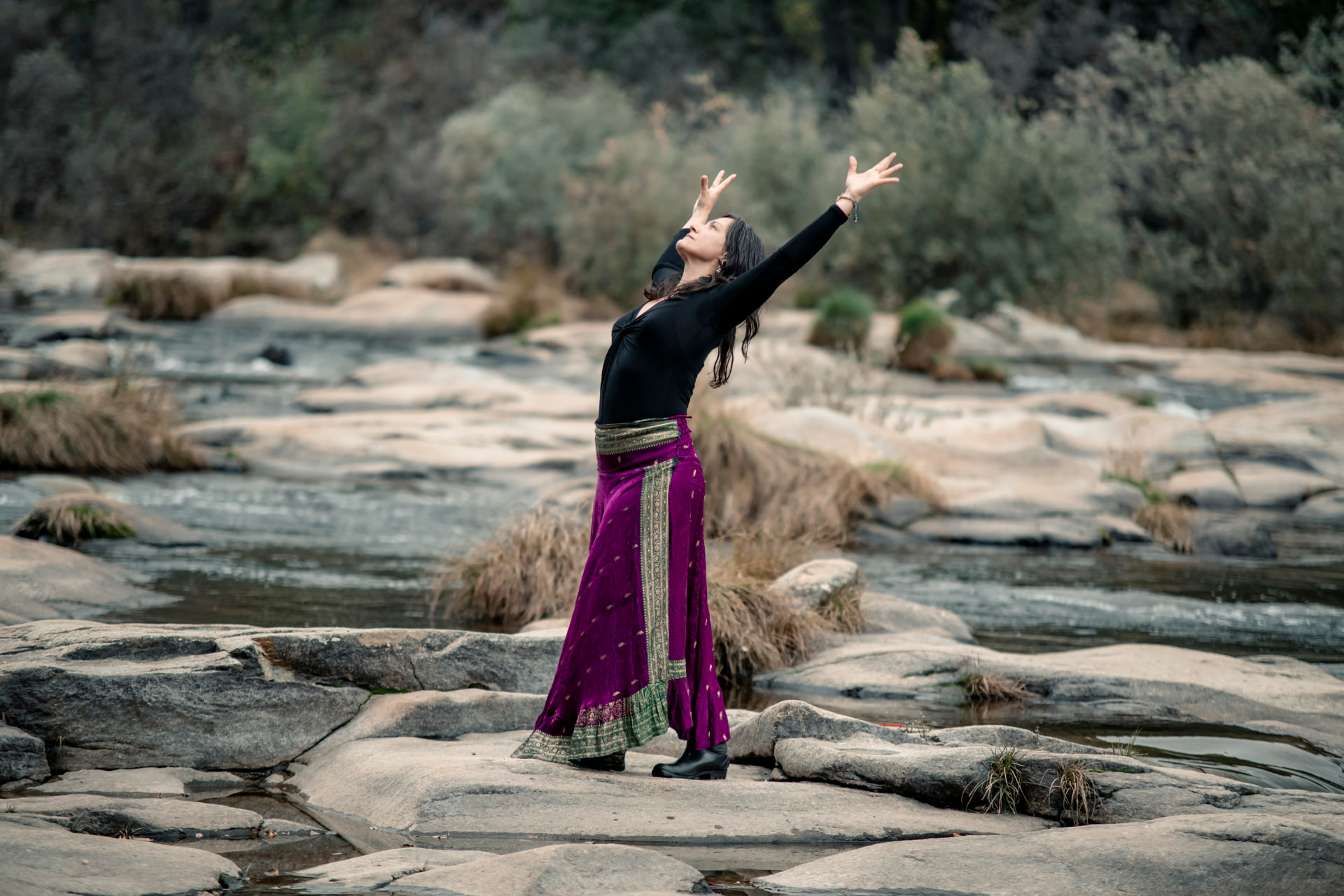 Valvanera Berenguer bailando junto al río, con los brazos abiertos hacia el cielo